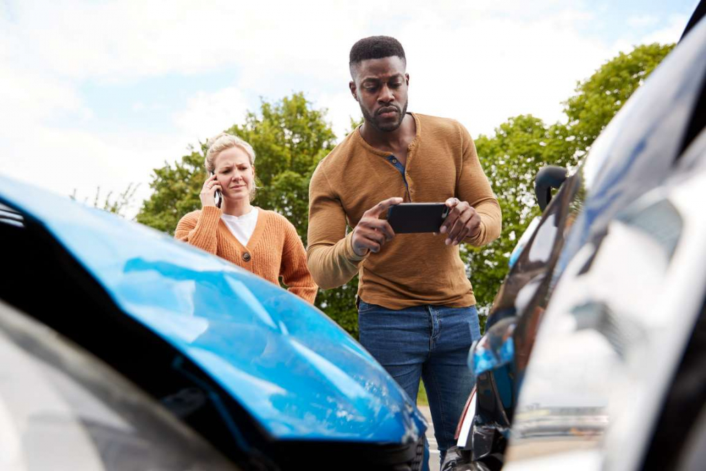 Motorist involved in car accident taking picture of damage for insurance claim